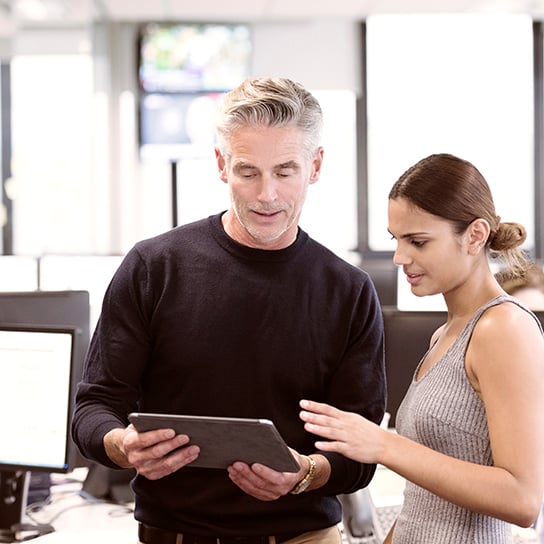 A woman and a man are watching a tablet
